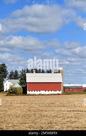 South Elgin, Illinois, Stati Uniti. Un moderno fienile rosso brillante oltre un campo di raccolti raccolti in un giorno d'autunno. Foto Stock