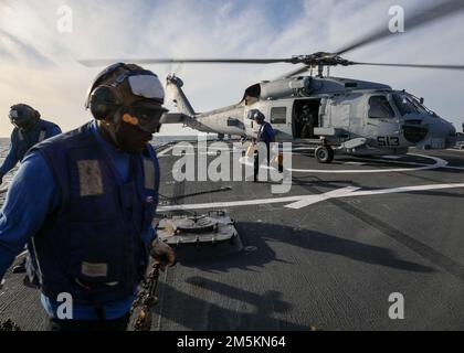 OCEANO ATLANTICO (22 marzo 2022) – i marinai rimuovono gessi e catene da un MH-60R Seahawk, assegnato ai 'Vipers' di Helicopter Maritime Strike Squadron (HSM) 48 sul ponte di volo del cacciatorpediniere missilistico guidato di classe Arleigh Burke USS Porter (DDG 78), marzo 22. Porter, schierato in futuro a Rota, Spagna, sta attualmente partecipando all'esercizio della Task Force nell'area operativa della flotta degli Stati Uniti 2nd. TFEX funge da esercizio di certificazione per l'implementazione indipendente di navi ed è progettato per testare la preparazione e le prestazioni della missione in operazioni integrate. Foto Stock