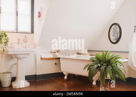 Lavabo bianco a piedistallo e vasca da bagno a scomparsa nella camera da letto principale al piano superiore, all'interno di una casa in legno ricostruita degli anni '1840. Foto Stock