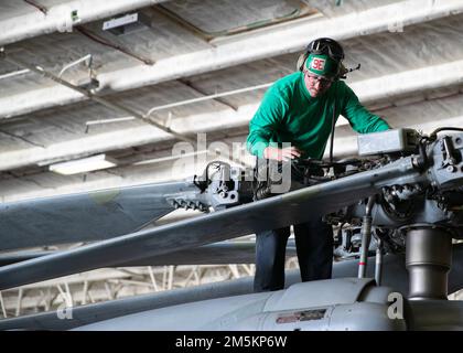 Aviation Electrician's Mate 2nd Class Tyler Ojeda, di Maywood, New Jersey, assegnato ai 'tridenti' di Helicopter Sea Combat Squadron (HSC) 9, esegue la manutenzione ordinaria su un MH-60s Nighthawk, attaccato a HSC-9, nella baia hangar di USS Gerald R. Ford (CVN 78), 23 marzo 2022. Ford è in corso nell’Oceano Atlantico per la certificazione del ponte di volo e la qualifica del vettore aereo come parte della fase di base su misura della nave prima dello spiegamento operativo. Foto Stock