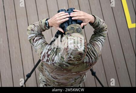 Un istruttore dell'esercito degli Stati Uniti John F. Kennedy Special Warfare Center and School guarda attraverso binocoli per osservare l'accuratezza di un concorrente nella United States Army Special Operations Command (USASOC) International Sniper Competition a Fort Bragg, North Carolina, 23 marzo 2022. Ventuno squadre hanno partecipato alla 13th edizione annuale della USASOC International Sniper Competition, in cui istruttori del United States Army John F. Kennedy Special Warfare Center and School hanno progettato una serie di eventi che hanno messo in discussione la capacità delle due squadre di lavorare insieme, il campo di tiro, la velocità e. Foto Stock