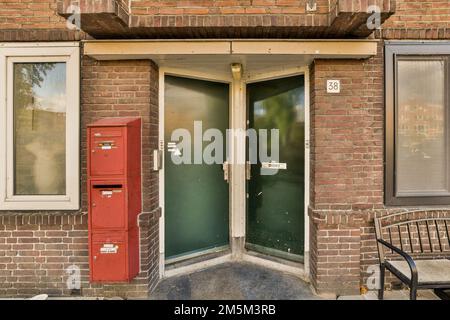 un edificio in mattoni con una porta verde e una cassetta postale rossa nella porta è visibile sul lato sinistro della foto Foto Stock