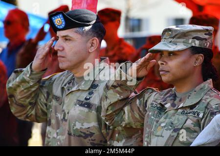 STATI UNITI Comando dell'esercito Sgt. Maj. Kristian Castro, a sinistra, l'entrante 41st campo Artillery Brigade Command Sergente maggiore e sua moglie Stati Uniti Il maggiore dell’esercito Natasha Fultz-Castro, ufficiale degli affari pubblici con 2nd reggimento di cavalleria, saluta all’inno nazionale durante la cerimonia di assunzione di responsabilità della brigata presso la Torre Barracks Grafenwoehr, in Germania, 24 marzo 2022. Foto Stock