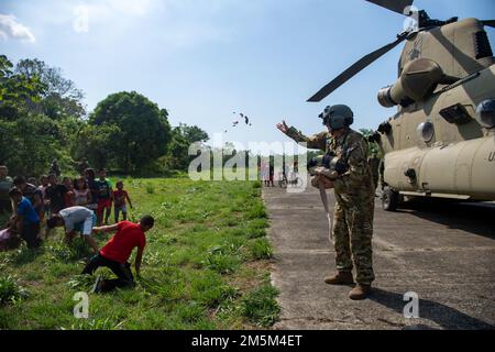 Un membro della Joint Task Force-Bravo’s 1st Battaglione, 228th Aviation Regiment, lancia caramelle ai bambini prima di partire da Sambu, Panama, 24 marzo 2022. 1-228th ha consegnato forniture per la costruzione di abitazioni alla provincia di Darien a sostegno dell'esercizio Mercurio III, un'attività di aiuto umanitario guidata da Panama e di soccorso in caso di catastrofi. Foto Stock