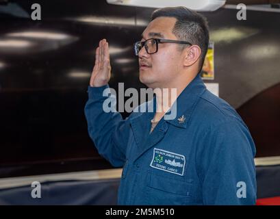 OKINAWA, Giappone (24 marzo 2022) Specialista 2nd Classe Alex Cabico, di Delano, California, recita il giuramento di arruolamento durante una cerimonia di riascolto a bordo del cacciatorpediniere missilistico guidato di classe Arleigh Burke USS Ralph Johnson (DDG 114). Ralph Johnson è assegnato alla Task Force 71/Destroyer Squadron (DESRON) 15, la più grande DESRON della Marina e la principale forza di superficie della flotta statunitense 7th. Foto Stock