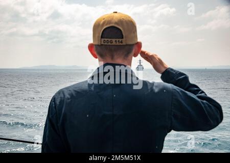OKINAWA, Giappone (24 marzo 2022) Seaman Shane Regenald, di Jacksonville, Florida, rende onore al cacciatorpediniere missilistico guidato di classe Arleigh Burke USS Momsen (DDG 92) a bordo del cacciatorpediniere missilistico guidato di classe Arleigh Burke USS Ralph Johnson (DDG 114). Ralph Johnson è assegnato alla Task Force 71/Destroyer Squadron (DESRON) 15, la più grande DESRON della Marina e la principale forza di superficie della flotta statunitense 7th. Foto Stock