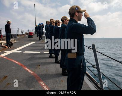 OKINAWA, Giappone (24 marzo 2022) marinai a bordo del cacciatorpediniere missilistico guidato classe Burke di Arleigh USS Ralph Johnson (DDG 114) rendono onore al cacciatorpediniere missilistico guidato classe Burke USS Momsen (DDG 92). Ralph Johnson è assegnato alla Task Force 71/Destroyer Squadron (DESRON) 15, la più grande DESRON della Marina e la principale forza di superficie della flotta statunitense 7th. Foto Stock
