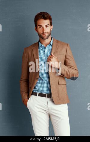 Alcuni lo chiamano l'esperto di stile. Studio ritratto di un giovane uomo elegantemente vestito che si posa su uno sfondo grigio. Foto Stock