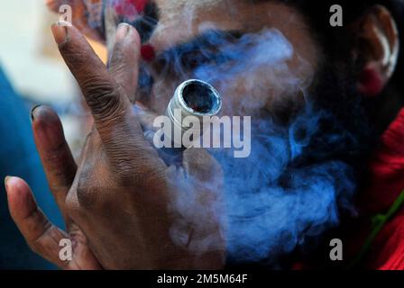 Un chillum sadhu Shaivite fumante sul Ghat Mallick presso il fiume Hooghly a Kolkata, India. Foto Stock