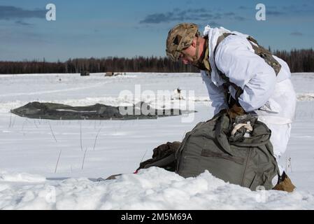 Un paracadutista dell'esercito assegnato a 1st Squadrone (Airborne), 40th reggimento di cavalleria, 4th squadra di combattimento della Brigata di Fanteria (Airborne), 25th divisione di Fanteria, Stati Uniti Army Alaska, recupera il suo paracadute durante l'addestramento aereo alla Malemute Drop zone, Joint base Elmendorf-Richardson, Alaska, 24 marzo 2022. Le unità dell'esercito e dell'aeronautica si addestrano regolarmente insieme per rafforzare e mantenere le abilità comuni di preparazione alla missione in un ambiente artico. Foto Stock