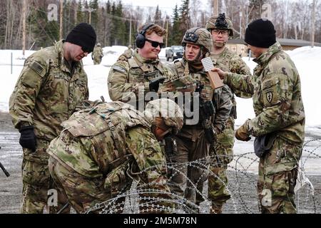 Paracadutisti assegnati a Dog Company, 3rd battaglione, 509th reggimento di fanteria paracadute, 4th squadra di combattimento di fanteria brigata (Airborne), 25th divisione di fanteria, Stati Uniti Army Alaska, allinea per disegnare munizioni prima di allenarsi con il fuoco da stress presso il campo di fuoco sportivo della base militare di Elmendorf-Richardson, Alaska, 24 marzo 2022. I soldati della Dog Company sono stati valutati in base al rapido coinvolgimento degli obiettivi di fuoco vivo, evacuando in sicurezza un incidente simulato sul campo di battaglia tramite una lettiera improvvisata SKED e rompendo il contatto su pericolosi terreni fangosi e ghiacciati. (STATI UNITI Air Force foto/Justin Connaher) Foto Stock