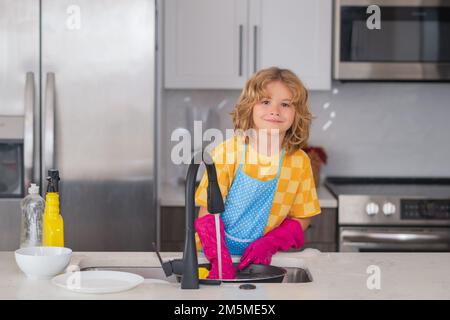 Ritratto di pulizia del bambino nel kithen a casa, la crescita del concetto, lo sviluppo, le relazioni familiari. La cameriera dei bambini lava i piatti su saponata Foto Stock