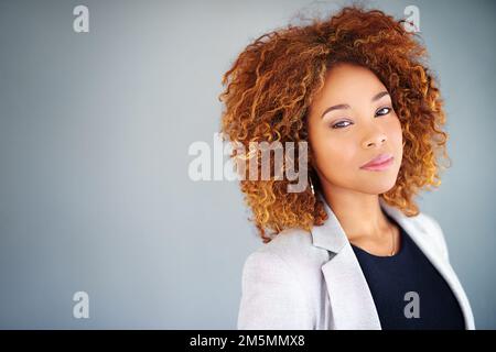 Fiducia nel mondo aziendale. Studio ritratto di una giovane donna d'affari su uno sfondo grigio. Foto Stock