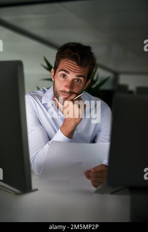 Mettere nelle ore per raggiungere il successo. un giovane uomo d'affari che lavora tardi in ufficio. Foto Stock