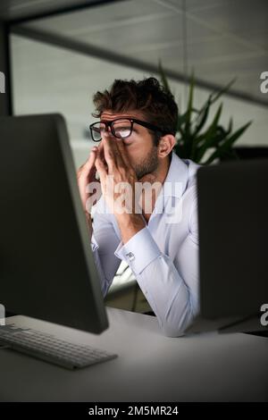 Mettere nelle ore per raggiungere il successo. un giovane uomo d'affari che lavora tardi in ufficio. Foto Stock