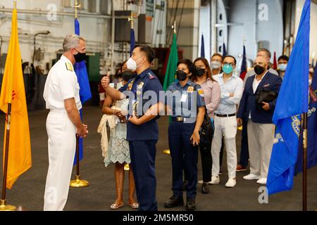 MANILA BAY, Filippine (27 marzo 2022) posteriore ADM. J.T. Anderson, comandante, Carrier Strike Group (CSG) 3, saluta i leader militari e civili delle Filippine quando arrivano nella baia dell'hangar a bordo della portaerei di classe Nimitz USS Abraham Lincoln (CVN 72). Mentre nelle Filippine, Abraham Lincoln ha celebrato il 70th° anno degli Stati Uniti Alleanza filippina attraverso attriti di visitatori distinti in mare, tour in nave, progetti di relazioni con la comunità, tour MWR e un ricevimento ospitato nella baia hangar della nave. Gli ospiti alla reception hanno incluso illustri visitatori filippini, senior government o Foto Stock