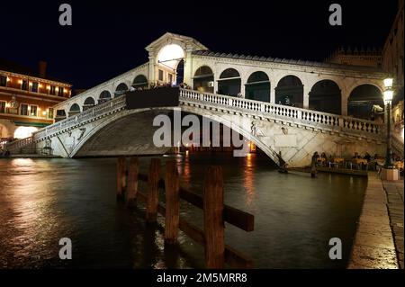 Vista notturna del Canal Grande di Venezia con il Ponte di Rialto sullo sfondo con persone che cenano sotto il ponte al chiaro di luna, Venezia, i Foto Stock