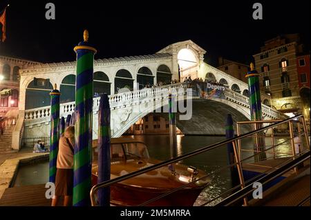 Vista notturna del ponte di Rialto e un taxi ormeggiato nelle tipiche colonne di colore veneziane, Venezia, Italia Foto Stock