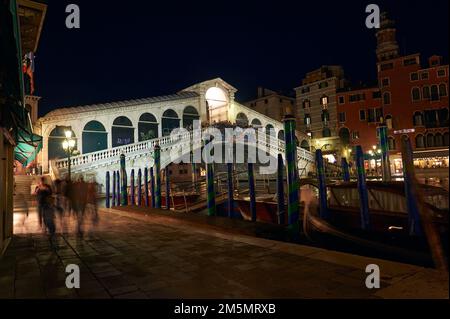 Vista notturna del ponte di Rialto e un taxi ormeggiato nelle tipiche colonne di colore veneziane, Venezia, Italia Foto Stock