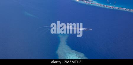 Paesaggio mare vista aerea sulle Maldive ville resort di lusso con atollo isola di sabbia. Moto d'acqua divertendosi nella laguna oceanica. Estate di lusso Foto Stock