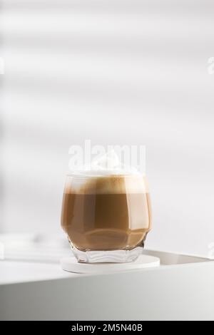Cappuccino in una tazza di vetro su un tavolo di legno bianco, Cappuccino con una schiuma di latte Foto Stock