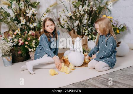 Due ragazze in una bellissima zona foto di Pasqua con fiori, uova, polli e coniglietti pasquali. Buona vacanza di Pasqua Foto Stock