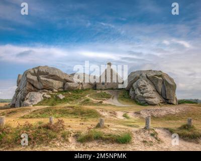 La Casa della Guardia (Corps de Garde) ('Casa doganale') tra due enormi rocce di granito, Site de Meneham, Meneham, Kerlouan, Dipartimento Finistere Foto Stock