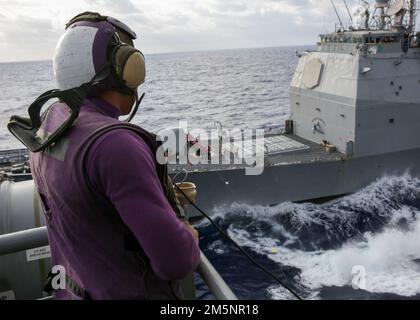 MARE DELLE FILIPPINE (26 febbraio 2022) Aviation Boatswain’s Mate (Fuel) Airman Matthew Pearson, di Houston, osserva un rifornimento in mare con l'incrociatore missilistico guidato di classe Ticonderoga USS Mobile Bay (CG 53) a bordo della portaerei di classe Nimitz USS Abraham Lincoln (CVN 72). Abraham Lincoln Strike Group è in fase di implementazione pianificata nell'area delle operazioni della flotta 7th degli Stati Uniti per migliorare l'interoperabilità attraverso alleanze e partnership e al tempo stesso fungere da forza di risposta pronta a sostegno di una regione indomPacifico libera e aperta. Foto Stock