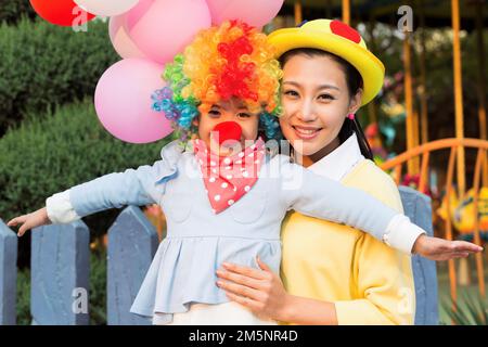 Una giovane madre e figlia vestita come un clown nel parco divertimenti per giocare Foto Stock