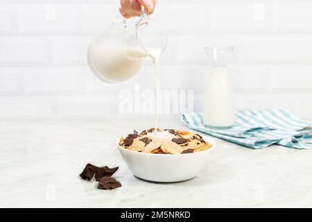 i fiocchi di mais nel recipiente e il latte fuoriesce dal biberon Foto Stock