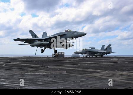 MARE DELLE FILIPPINE (26 febbraio 2022) un F/A-18E Super Hornet, assegnato ai “Tophatters” di Strike Fighter Squadron (VFA) 14, si prepara a fare un atterraggio arrestato sul ponte di volo della portaerei di classe Nimitz USS Abraham Lincoln (CVN 72). Abraham Lincoln Strike Group è in fase di implementazione pianificata nell'area delle operazioni della flotta 7th degli Stati Uniti per migliorare l'interoperabilità attraverso alleanze e partnership e al tempo stesso fungere da forza di risposta pronta a sostegno di una regione indomPacifico libera e aperta. Foto Stock