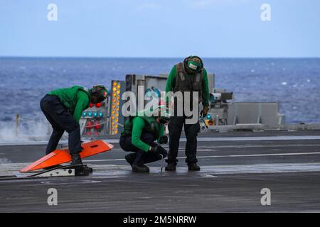 MARE DELLE FILIPPINE (26 febbraio 2022) i marinai preparano il ponte di volo per le operazioni di volo di recupero a bordo della portaerei di classe Nimitz USS Abraham Lincoln (CVN 72). Abraham Lincoln Strike Group è in fase di implementazione pianificata nell'area delle operazioni della flotta 7th degli Stati Uniti per migliorare l'interoperabilità attraverso alleanze e partnership e al tempo stesso fungere da forza di risposta pronta a sostegno di una regione indomPacifico libera e aperta. Foto Stock