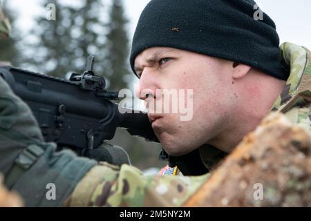 Un Guardsman nazionale dell'esercito dell'Alaska assegnato al distaccamento dell'utilità dell'ingegnere 207th difende una posizione di combattimento artico durante un'esercitazione di addestramento sul campo di operazioni congiunte a Camp Mad Bull sulla base congiunta Elmendorf-Richardson, Alaska, 26 febbraio 2022. L'esercizio consisteva in operazioni di sollevamento aereo, costruzione di posizioni artiche di combattimento difensivo, e un attacco simulato di armi leggere progettato per valutare e rafforzare le risposte da parte dell'aeronautica e del personale della Guardia Nazionale dell'Alaska Army. Le esercitazioni congiunte dimostrano la cooperazione, migliorano l'interoperabilità e ampliano la deterrenza. Foto Stock