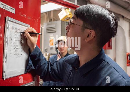 220223-N-XB010-1004 EAST CHINA SEA (23 febbraio 2022) Lt. j.g. Aaron Lee, di Saipan, nelle Isole Marianne Settentrionali, mantiene una lista di controllo durante un'esercitazione generale a bordo della USS New Orleans (LPD 18). New Orleans, parte dell'America Amphibious Ready Group, insieme alla Marine Expeditionary Unit 31st, opera nell'area di responsabilità della flotta 7th degli Stati Uniti per migliorare l'interoperabilità con alleati e partner e fungere da pronta forza di risposta per difendere la pace e la stabilità nella regione dell'Indo-Pacifico. Foto Stock