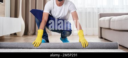 Primo piano di uomo che srotola moquette. Concetto di servizio di pulizia Foto Stock