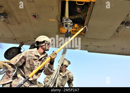 SPC. Aliah Rodriquez tiene un'asta di messa a terra mentre PFC. Randy Sanchez aggancia le corde a un elicottero CH-47 Chinook assegnato a 1st Brigata dell'Aviazione di combattimento durante un'operazione di carico congiunto con la 16th squadra britannica di combattimento aereo di assalto a Camp Pistolero, Kuwait, 25 febbraio 2022. I soldati sono assegnati a 389th battaglione di supporto di combattimento. Foto Stock