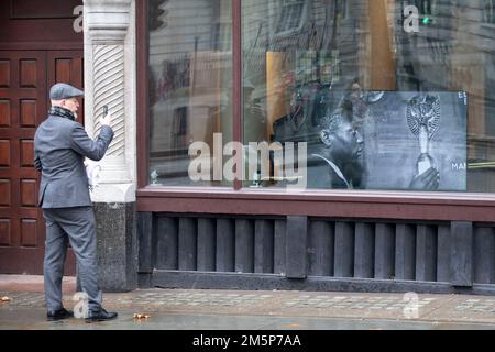 Un uomo scatta una foto di una presentazione di immagini che mostra il calciatore Pele nella finestra dell'Ambasciata brasiliana a Londra in seguito alla morte del tre volte vincitore della Coppa del mondo il giovedì a San Paolo.Data foto: Venerdì 16 dicembre 2022. Foto Stock