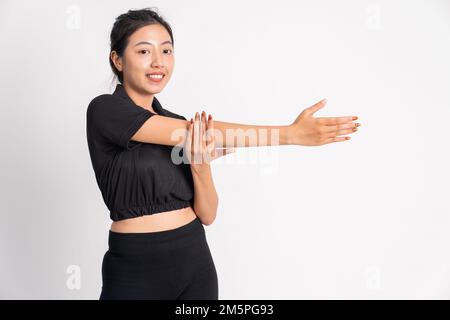 donna asiatica in tuta nera allungando le mani su sfondo isolato Foto Stock