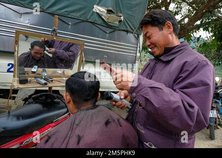 Bac ha, Vietnam - 18 dicembre 2022: Un barbiere che taglia i capelli di un cliente al mercato di Bac ha in Vietnam. Foto Stock