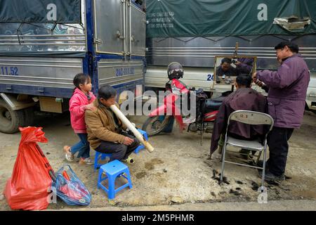 Bac ha, Vietnam - 18 dicembre 2022: Un barbiere che taglia i capelli di un cliente al mercato di Bac ha in Vietnam. Foto Stock