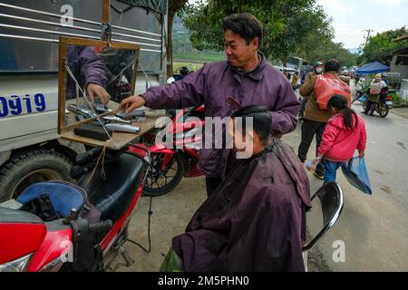 Bac ha, Vietnam - 18 dicembre 2022: Un barbiere che taglia i capelli di un cliente al mercato di Bac ha in Vietnam. Foto Stock