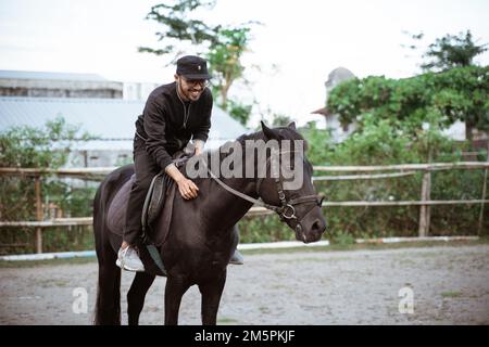 uomo in nero a cavallo nero Foto Stock