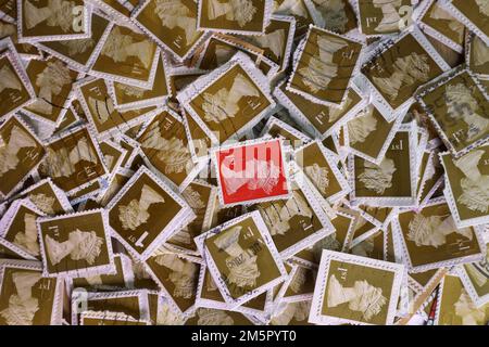 Usato UK franked francobolli di affrancatura che sono collectd per un contributo di carità. Una selezione colorata di francobolli di uso Royal Mail britannici in primo piano. Regno Unito contrasto del francobollo rosso di prima classe sullo sfondo dei francobolli marroni di prima classe (1st) Foto Stock