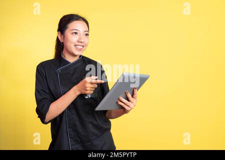 entusiasta cuoco asiatico femminile che utilizza un tablet digitale Foto Stock