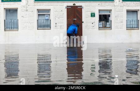 Un negoziante chiude il suo negozio nelle Whitesands, Dumfries, a causa delle inondazioni causate dallo straripamento del fiume Nith. Un avvertimento meteorologico ambrato di pioggia pesante è stato emesso per parte della Scozia come il Met Office ha detto che il ciclone mortale della bomba che ha inviato le temperature che precipitavano negli Stati Uniti ora sta causando il tempo bagnato e ventoso nel Regno Unito. Data immagine: Venerdì 30 dicembre 2022. Foto Stock