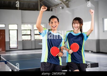 Due giocatori di ping pong che tengono pagaie con pugni sollevati Foto Stock