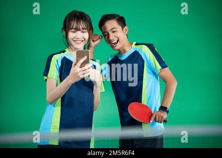 atleti di sesso femminile e maschile eccitati mentre guardano gli smartphone Foto Stock