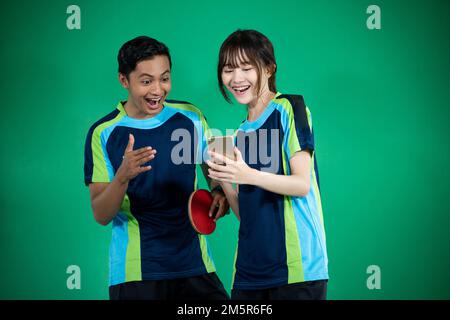 Atleti asiatici di sesso femminile e maschile entusiasti di guardare gli smartphone Foto Stock