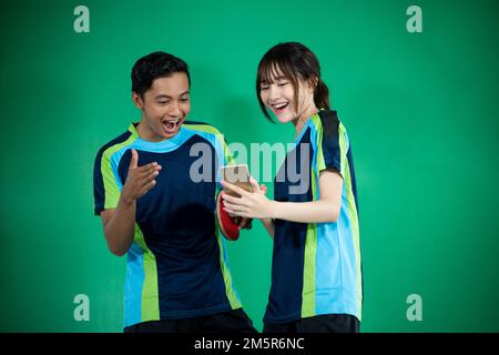 atleti di sesso femminile e maschile sono molto entusiasti di vedere smartphone Foto Stock
