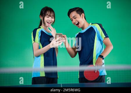 atleti di sesso femminile e maschile ridendo guardando i telefoni cellulari insieme Foto Stock